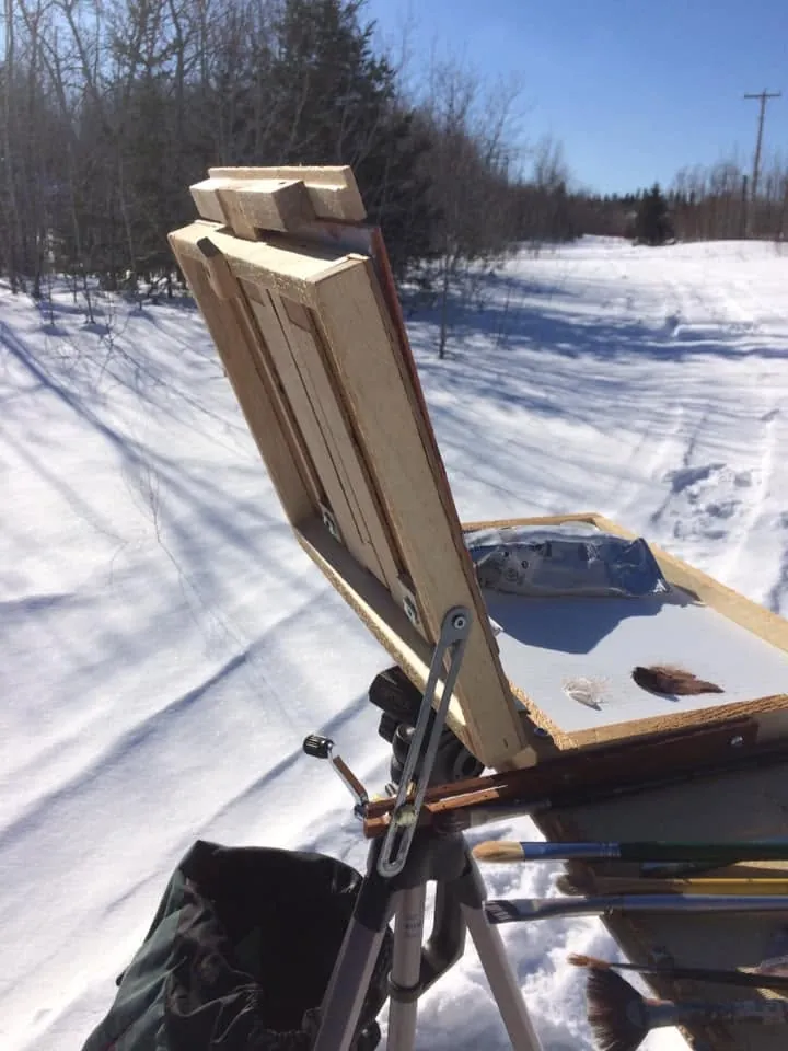 Chevalet portable en bois installé dans la neige, une petite toile dessus