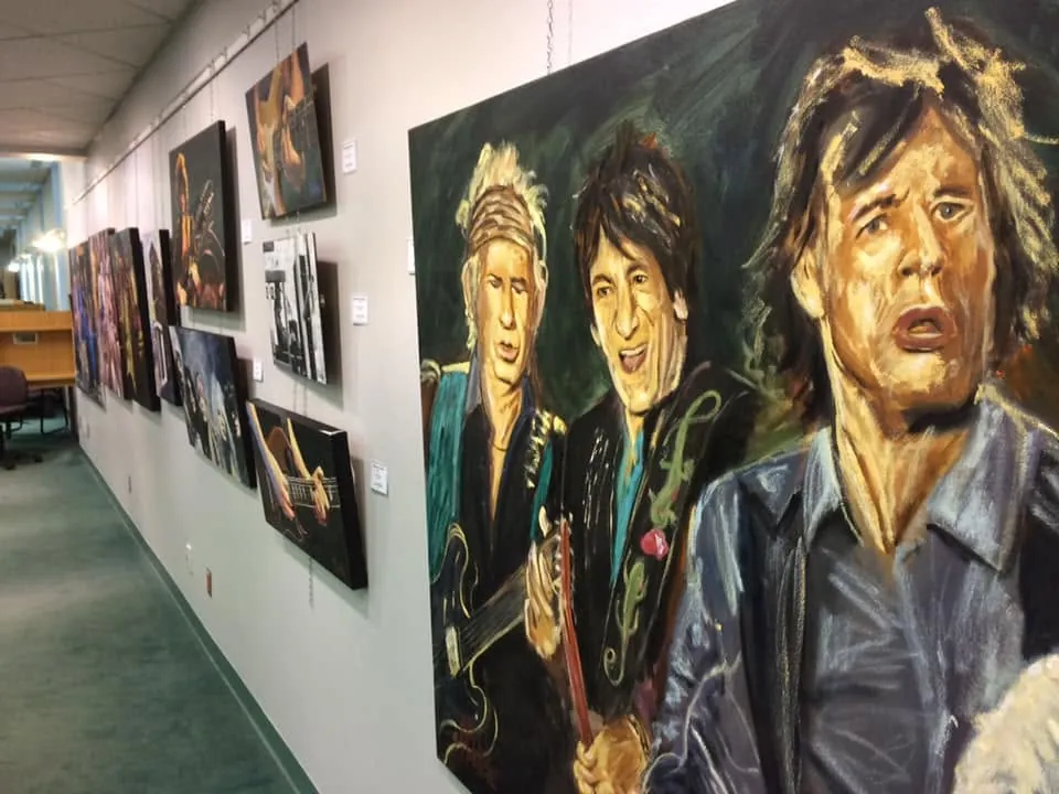 Corridor de la bibliothèque d'Alma avec une rangée de toiles de musiciens accrochées au mur