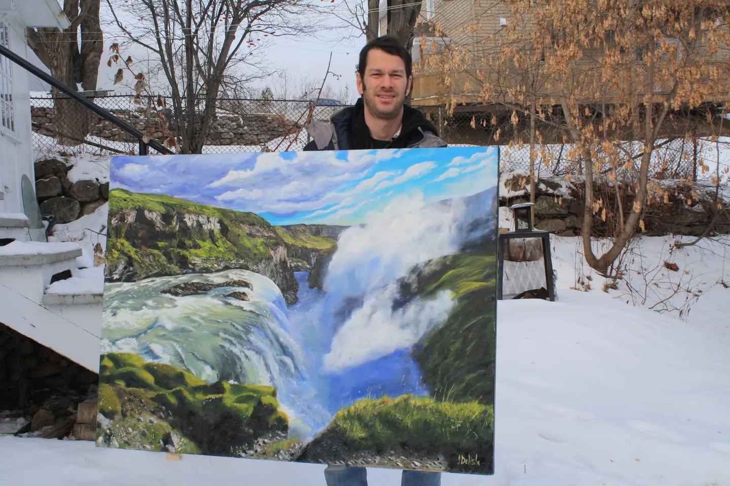 Jean Delisle tient la grande toile de Gullfoss dehors, dans la neige