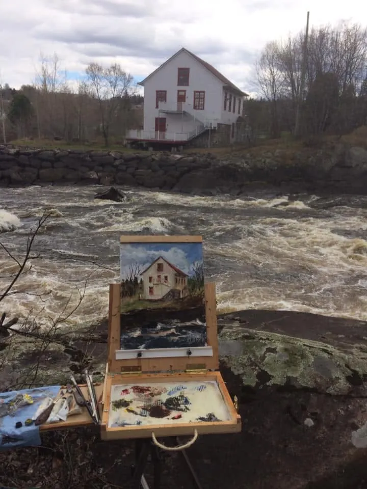 Le chevalet devant le Moulin Riverin, la rivière en rapides au premier plan