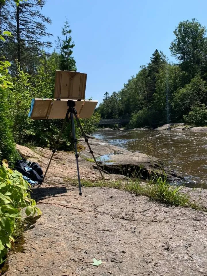 Le chevalet installé sur les rochers au bord de la rivière du Moulin, sous les arbres