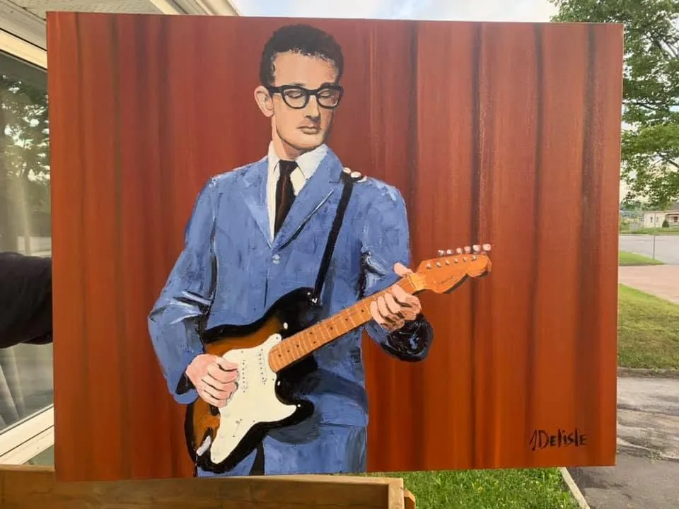 Buddy Holly en complet bleu et lunettes, Stratocaster à la main, devant un rideau rouge
